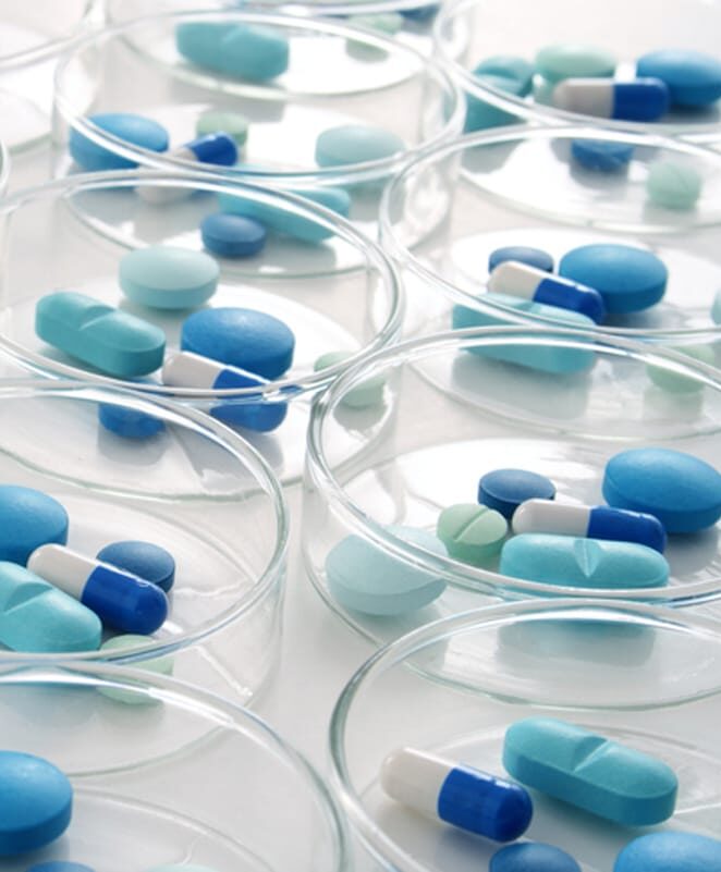 Pharmaceutical capsules arranged in petri dishes, illustrating the precision and control required in clinical trials logistics.