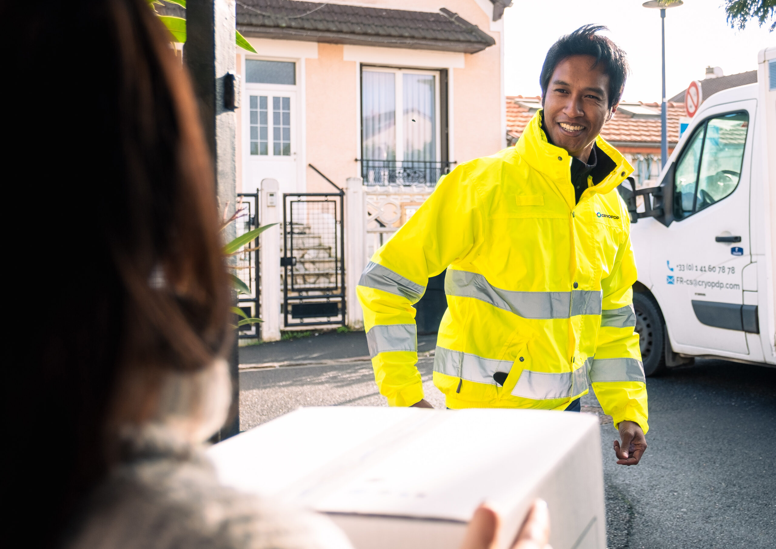 CRYOPDP courier in high-visibility gear handing over a package to a customer, illustrating white gloves delivery in healthcare logistics.