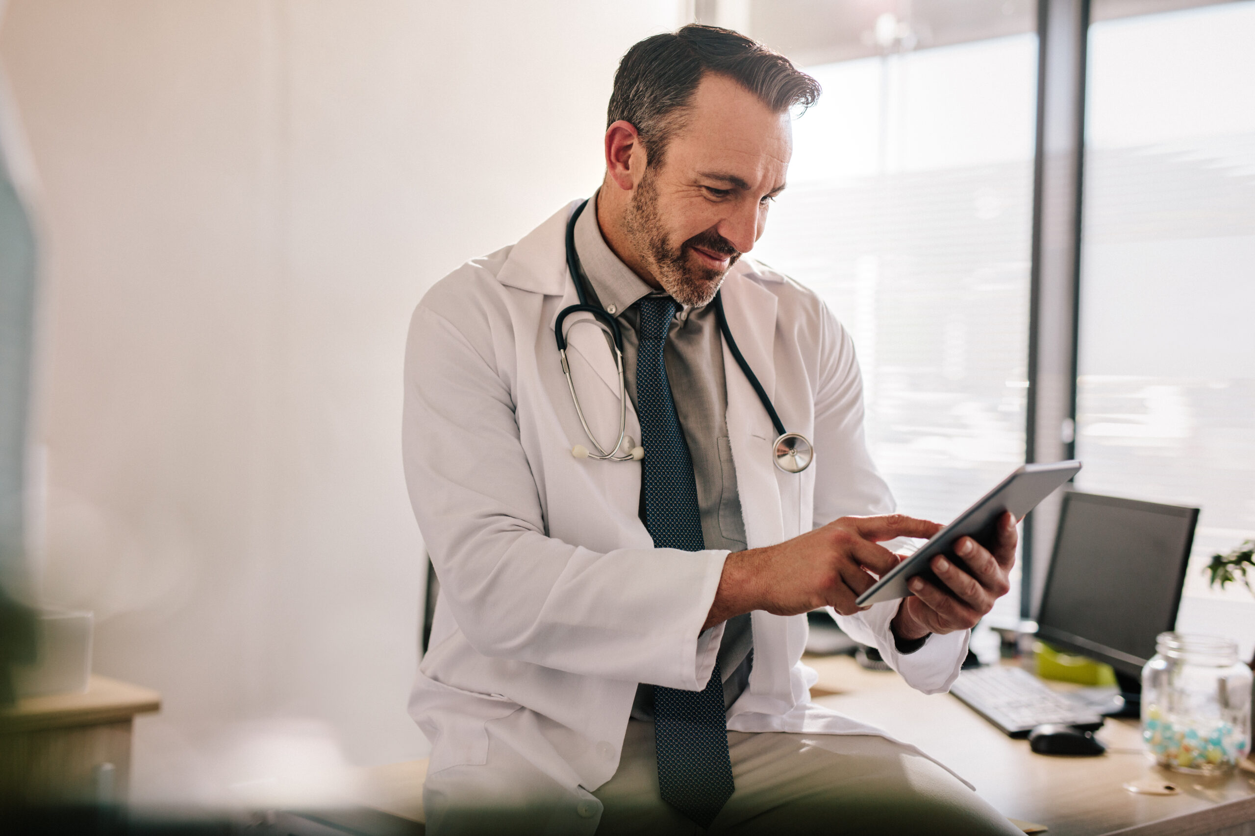 Doctor reviewing patient or shipment data on a digital tablet in a clinic office