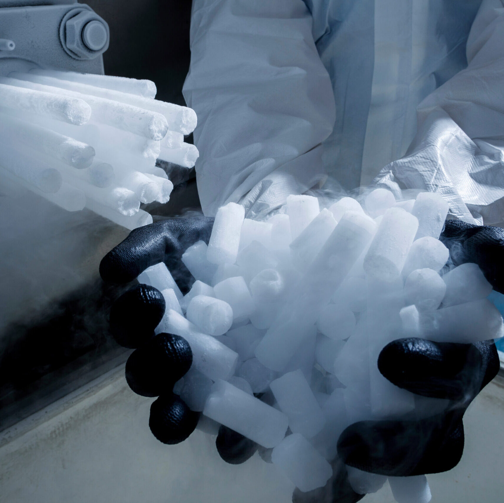Gloved hands holding dry ice pellets in a controlled environment, representing cold chain precision in healthcare logistics.