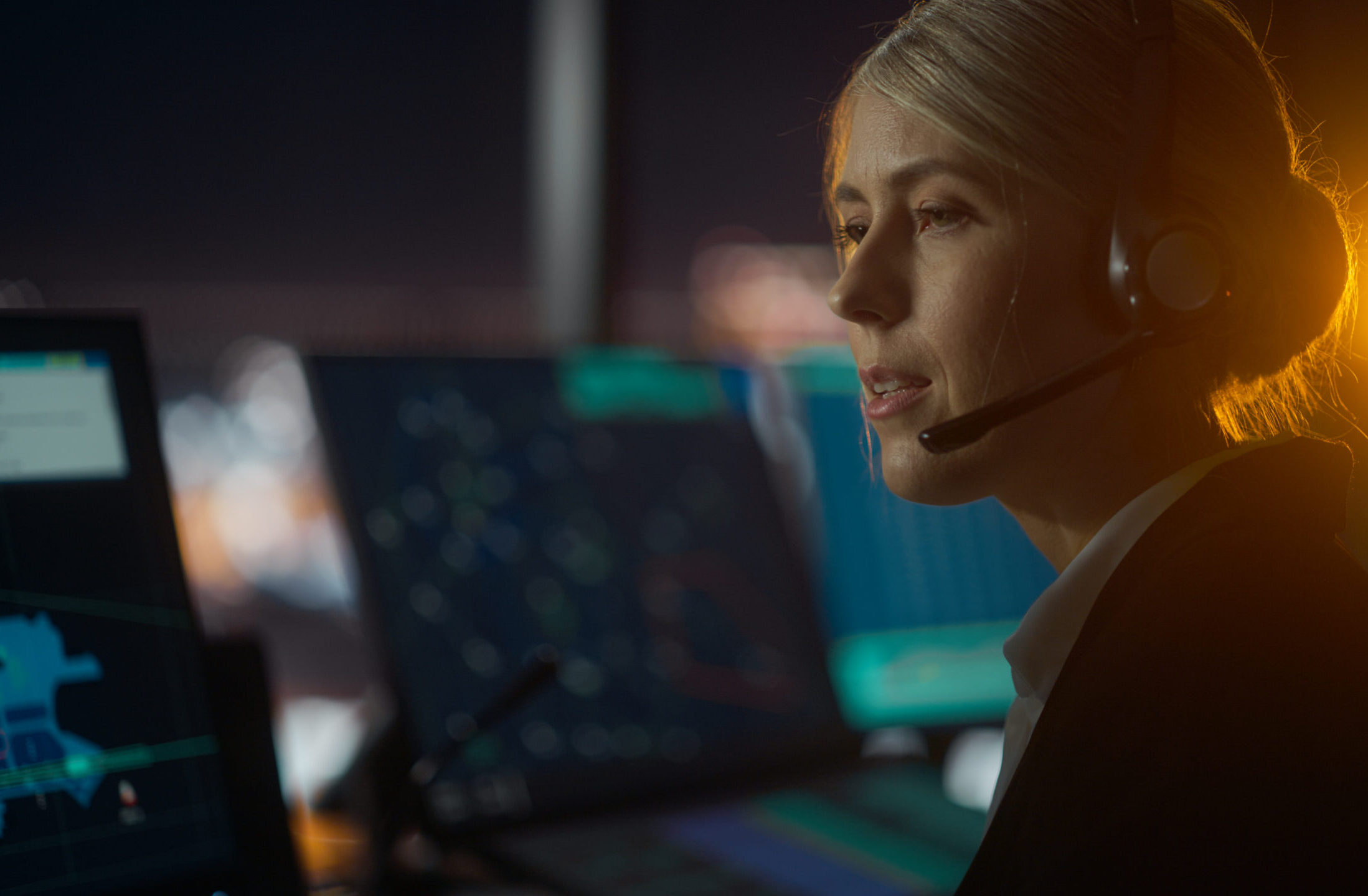 Logistics coordinator wearing a headset monitoring real-time data on multiple screens