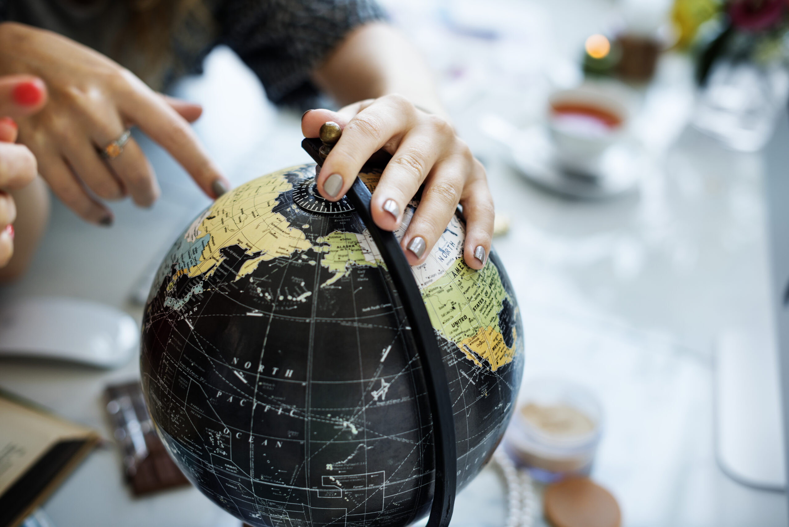 Close-up of hands exploring a globe, symbolising international logistics and planning for distribution services.