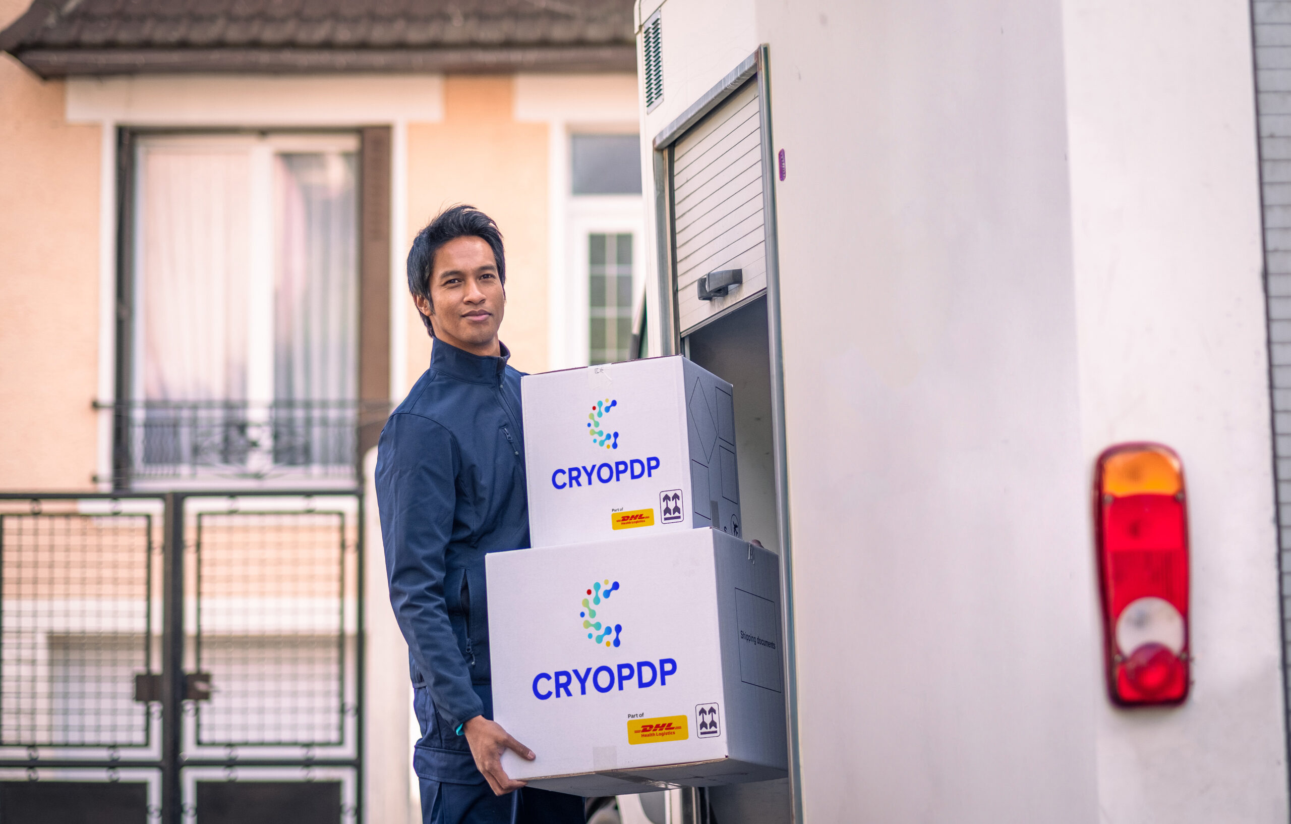 Team member loading CRYOPDP boxes into a temperature-controlled vehicle outside a healthcare facility