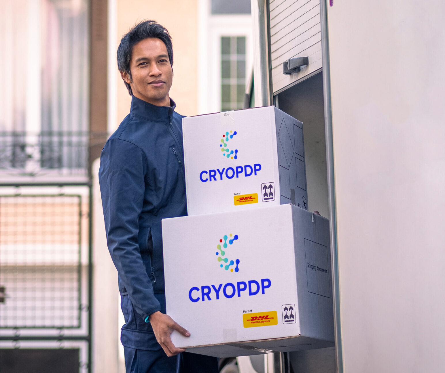 Courier loading CRYOPDP temperature-controlled boxes into a vehicle, representing cold chain logistics in healthcare.