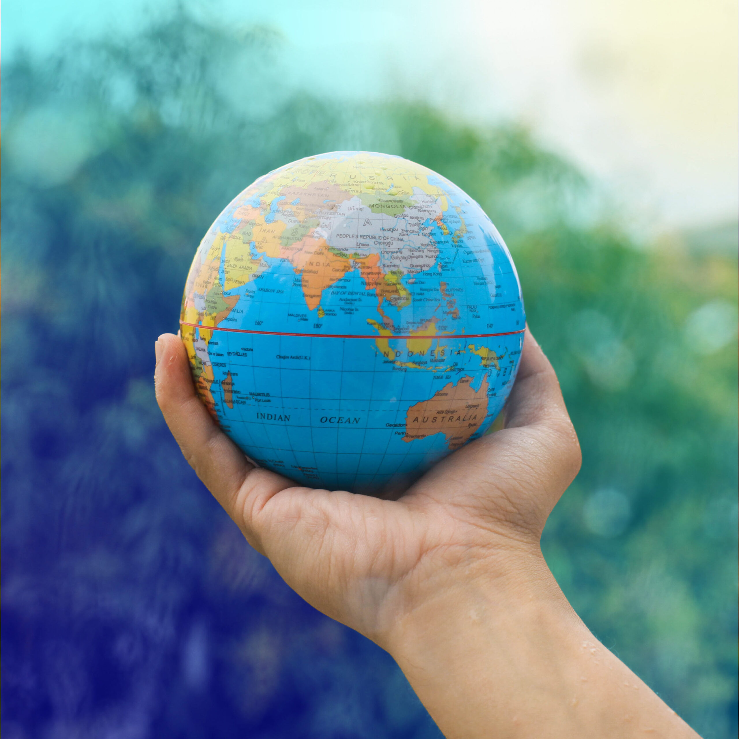 Hand holding a globe against a natural background, symbolising CRYOPDP’s global reach in temperature-controlled healthcare logistics