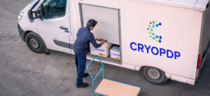 Courier loading a shipment into a CRYOPDP-branded delivery van using a trolley.